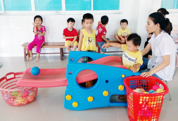 Kỹ thuật viên khoa PHCN Nhi Bệnh viện PHCN Đà Nẵng hướng dẫn trẻ tự kỷ chơi trò ném bóng vào giỏ. Ảnh: V.T.L