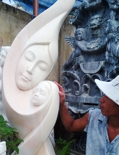 Anh Huỳnh Đăng Đức với tác phẩm điêu khắc “Mẹ con”. Ảnh: H.N