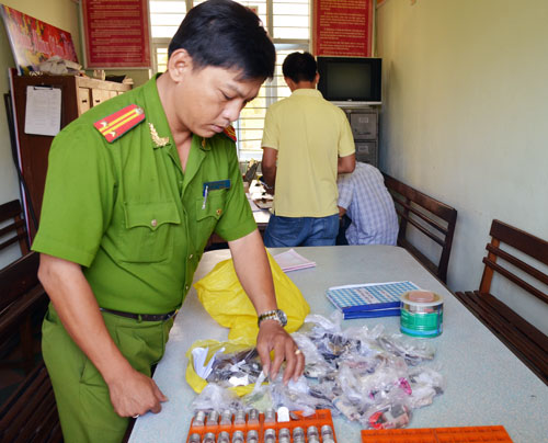 Trung tá Kiều Văn Vương, Phó Trưởng Công an quận Thanh Khê kiểm tra tang vật của một vụ đánh bạc. 			        Ảnh: NGỌC PHÚ