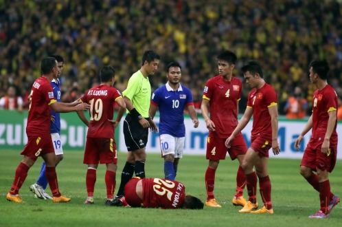 Huy Toàn (25) nằm trên sân sau khi trúng “đòn” từ đội Malaysia - Ảnh: N.K.