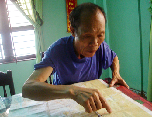 Ông Đinh Trần Thụ xác định vị trí chôn liệt sĩ trên bản đồ. Ảnh: N.CẦU