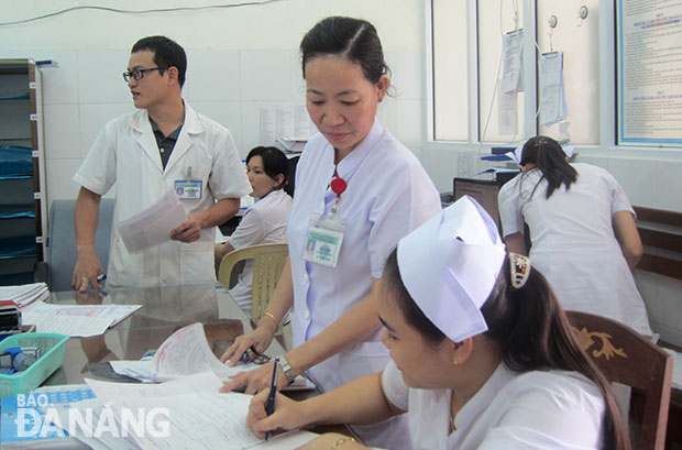 Chị Võ Thị Điềm (đứng) điều dưỡng trưởng khoa Ngoại chấn thương-chỉnh hình, BV Đà Nẵng đang trao đổi công việc hằng ngày với đồng nghiệp.