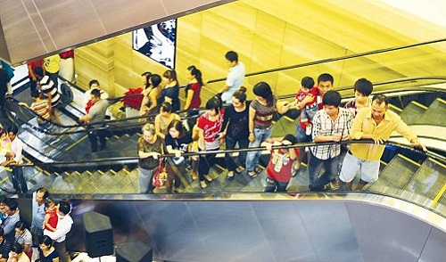 Shoppers stand on an escalator at a Vincom center in Ho Chi Minh City.