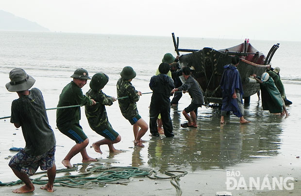 Chiến sĩ Đồn Biên phòng Sơn Trà giúp ngư dân kéo tàu vào bờ.