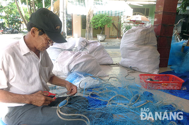 Lão ngư Từ Văn Ky dù đã “về hưu” nhưng vẫn phụ giúp các con quản lý hậu cần, sửa chữa ngư lưới cụ. Ảnh: Q.T