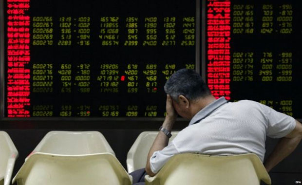 Người đàn ông ở Bắc Kinh (Trung Quốc) gục đầu khi bảng thị trường chứng khoán Trung Quốc thể hiện chỉ số giảm.