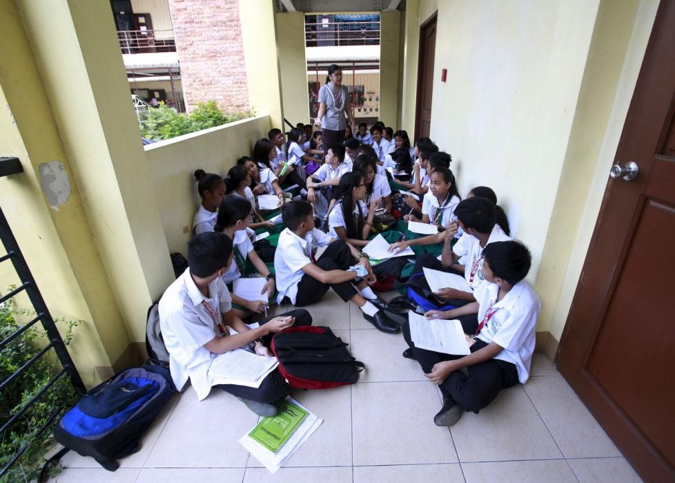 Cô giáo Kristine Passag và học sinh lớp 9 trường Timoteo Paez ở Manila (Philippines) học ngoài hành lang vì thiếu phòng. 