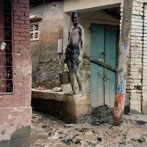 Chàng thanh niên đang nỗ lực đưa bùn đất ra khỏi nhà của mình ở thành phố Gonaives (Haiti). Cơn bão mạnh năm 2008 đã đánh vỡ bờ bao sông La Quinta làm nước ngập thành phố, làm chết hàng trăm người. Nước rút đi để lại lớp bùn dày cộm khiến người dân vô cùng vất vả để ổn định cuộc sống.