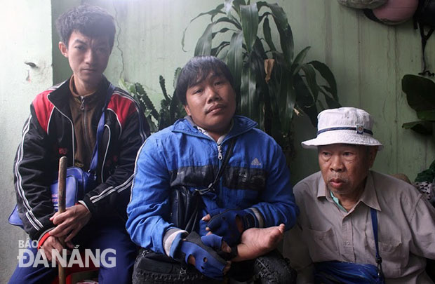  Ông Lê Văn Long (bên phải) và hai người khuyết tật khác đang tập trung nhận vé số tại đại lý trên đường Lê Độ. Ảnh: T.Y