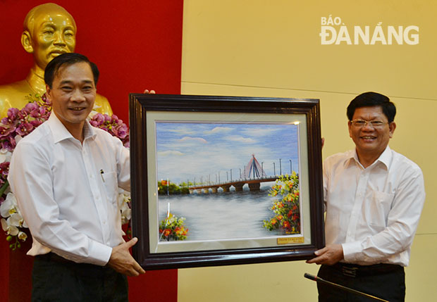 Phó Bí thư Thường trực Thành ủy Võ Công Trí tặng bức tranh cầu Sông Hàn-Đà Nẵng cho Tỉnh ủy Quảng Ninh. Ảnh: VIỆT DŨNG