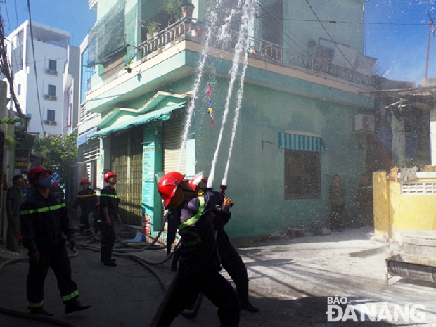 Lực lượng Cảnh sát PCCC chữa cháy nhà dân trong một đường kiệt. Ảnh: NAM TRÂN