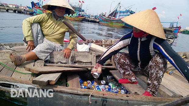 Nhiều người tranh thủ vớt chai nhựa, vỏ lon trôi nổi trên mặt sông để kiếm thêm thu nhập.  