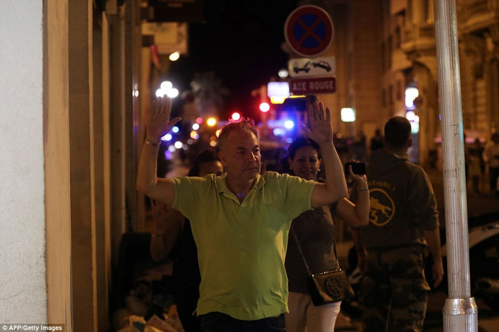 Một người dân Pháp đang nhanh chóng rời khỏi hiện trường vụ tấn công, với 2 cánh tay giơ cao trên đầu để rà soát an ninh. (ảnh: AFP). 