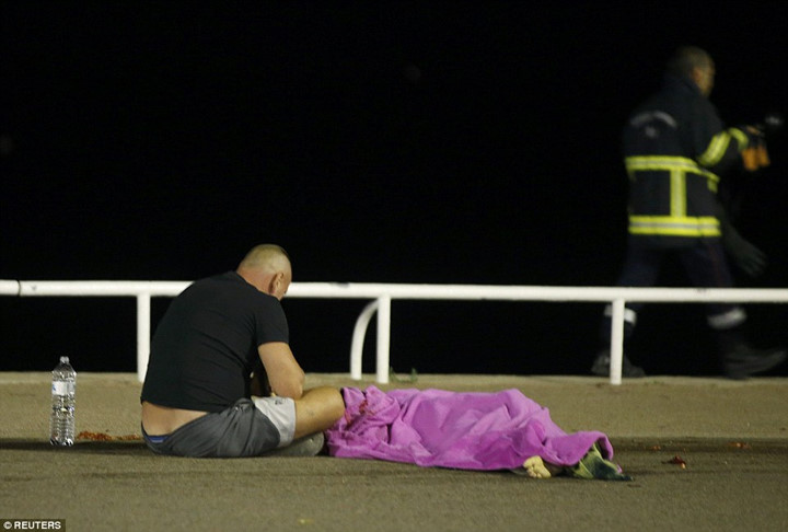 Một nhân chứng sau vụ tấn công vẫn còn choáng váng, ngồi lặng lẽ cầu nguyện cho bạn bè, người thân. (ảnh: Reuters). 