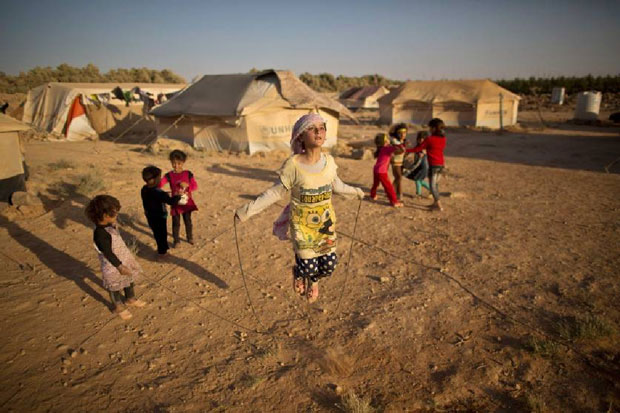 Cô bé Syrian, Zubaida Faisal, 10 tuổi, nhảy dây trong khi những đứa trẻ khác chơi gần lều của họ tại một khu định cư không chính thức gần biên giới Syria ở ngoại ô Mafraq, Jordan, ngày 19-7-2015.