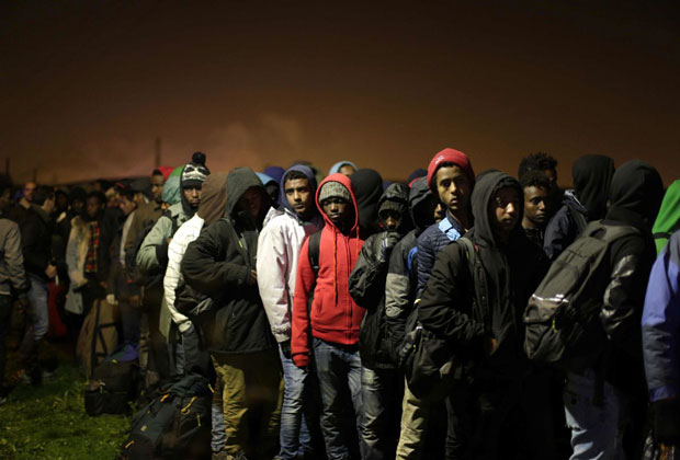 Những người di cư xếp hàng chờ lên xe buýt để đến các trung tâm tị nạn.      Ảnh: AP