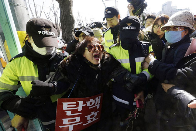 Cảnh sát bắt giữ một người tham gia tuần hành phản đối việc luận tội Tổng thống Park Geun-hye bên ngoài Tòa án Hiến pháp ngày 27-2. 									Ảnh: AP