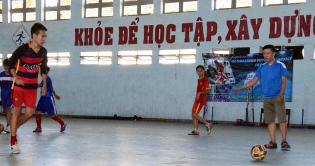 Thầy Lê Đắc Chí (áo xanh, phải) đang hướng dẫn bài tập sút bóng cho các thành viên của đội bóng đá Trường THCS Huỳnh Thúc Kháng.             Ảnh: ANH VŨ
