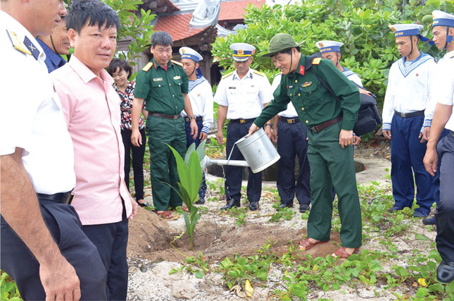 Đại tá - Nhà báo Trần Trọng Tuấn (người đang tưới nước) tham gia trồng cây lưu niệm ở đảo Nam Yết.Ảnh: N.P