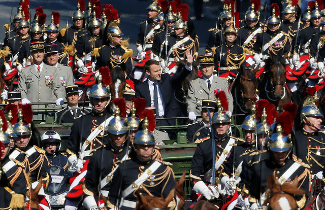 Tổng thống Pháp Emmanuel Macron vẫy tay chào công chúng khi đứng cạnh Tổng tham mưu trưởng các lực lượng vũ trang Pháp Pierre de Villiers trên chiếc xe jeep quân sự. (Ảnh: Reuters)