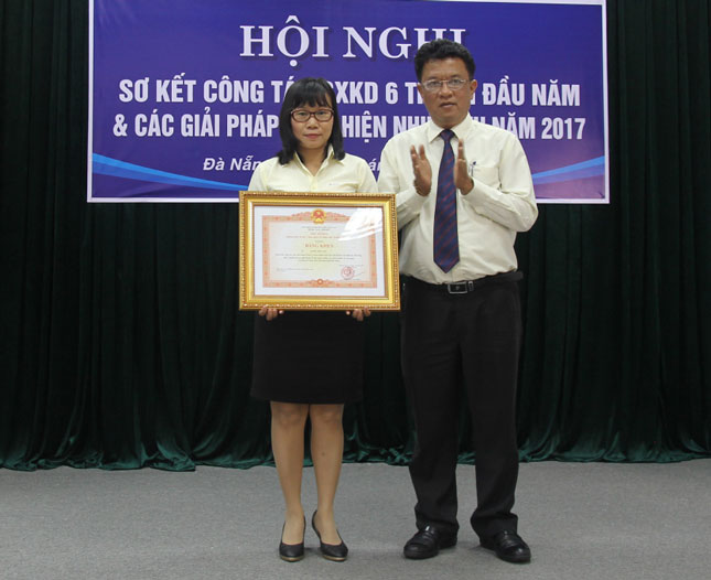 Ông Ngô Tấn Cư, Giám đốc Điện lực Đà Nẵng thừa ủy nhiệm trao Bằng khen của Thủ tướng Chính phủ cho chị Trần Thị Anh.