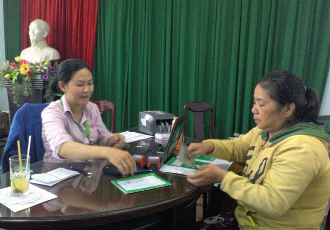 Bà Huỳnh Thị Thu Hằng (phải) nhận tiền vay sinh viên cho con tại buổi giải ngân của Phòng Giao dịch Ngân hàng Chính sách xã hội quận Liên Chiểu sáng 28-9-2017. Ảnh: V.T.L 