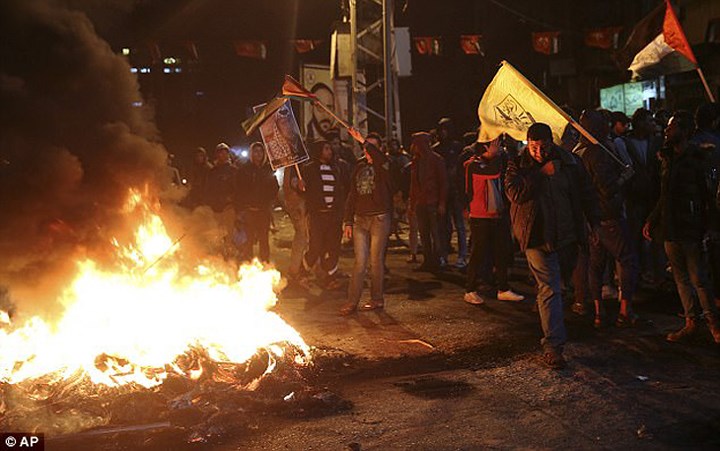 Người biểu tình Palestine đốt lốp ô tô, giương cao quốc kỳ Palestine và hình ảnh cố Tổng thống Yasser Arafat tại quảng trường chính ở Gaza. Ảnh: AP.