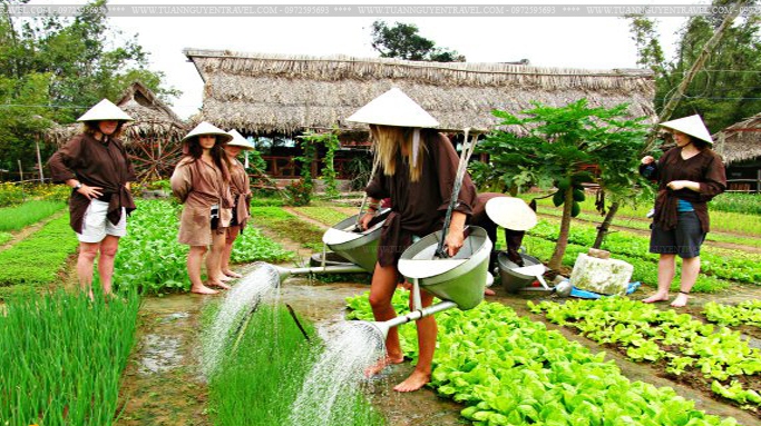 Be a farmer: A foreign tourists try watering vegetables in Tra Que village, Hoi An city, Quang Nam province.