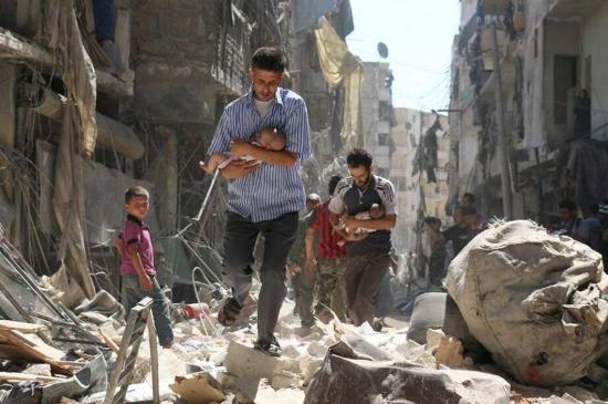 Người Syria đưa các em nhỏ ra khỏi đống đổ nát ở Aleppo hồi năm 2016. Ảnh: Getty Images