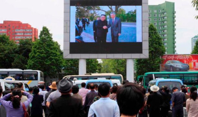 Người dân Bình Nhưỡng theo dõi bản tin về chuyến đi tới Singapore của nhà lãnh đạo Kim Jong-un từ màn hình lớn. (Ảnh: AP)
