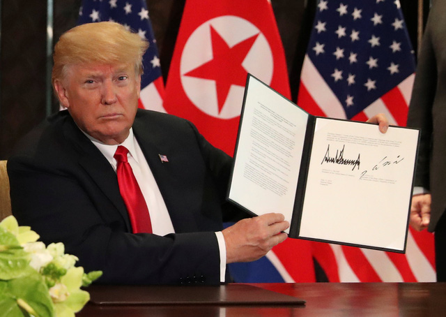 Tổng thống Trump giơ tuyên bố chung Mỹ - Triều sau khi ký kết cùng nhà lãnh đạo Kim Jong-un (Ảnh: Reuters)