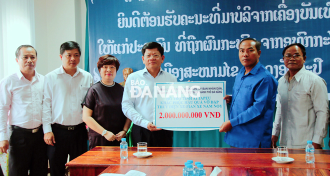 Phó Bí thư Thường trực Thành ủy Võ Công Trí (thứ tư, từ trái sang) trao số tiền 2 tỷ đồng cho chính quyền tỉnh Attapeu