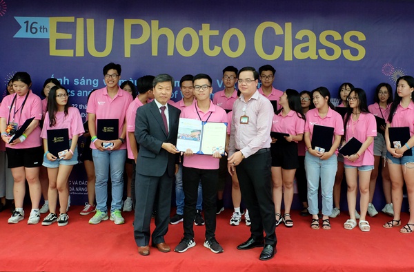 A pupil receiving a certificate of finishing EIU Photo Class 