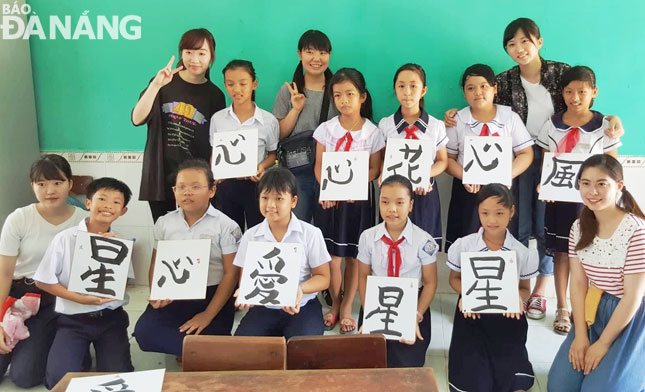 Japanese youths teaching Vietnamese children how to do calligraphy