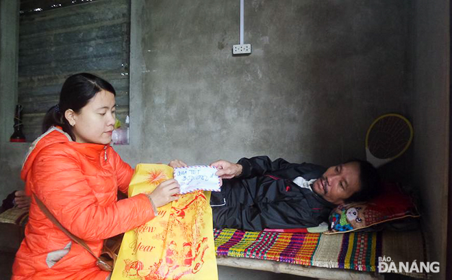 Trang presenting Tet gifts to a needy man during her charitable trip 	 