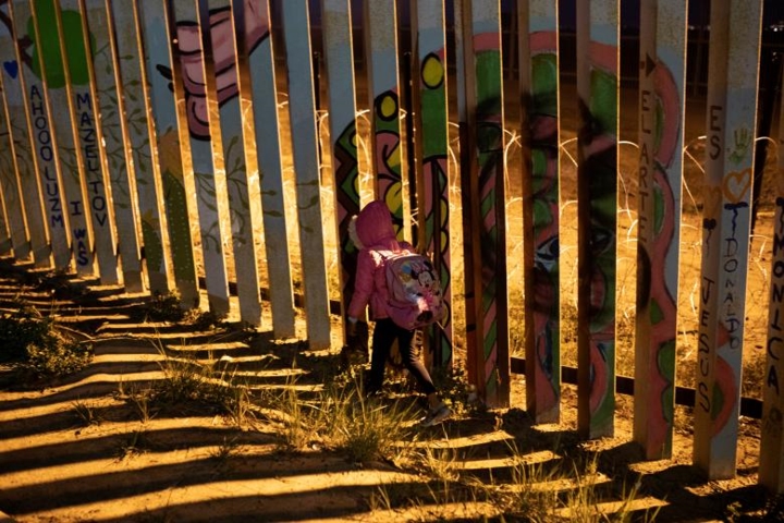 Bé gái nhập cư đi cạnh tường biên giới ở Tijuana, Mexico, vào ngày 2/12. Người nhập cư sang Mỹ vì lý do kinh tế hoặc để chạy trốn bạo lực