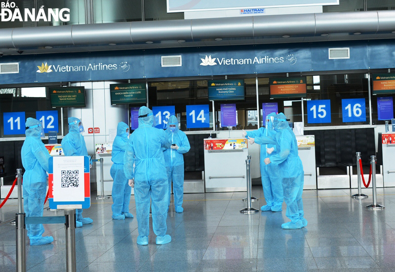 Nhân viên sân bay cũng trang bị đồ bảo hộ, trao đổi trước khi bắt đầu đón khách làm thủ tục. Ảnh: THU HÀ.