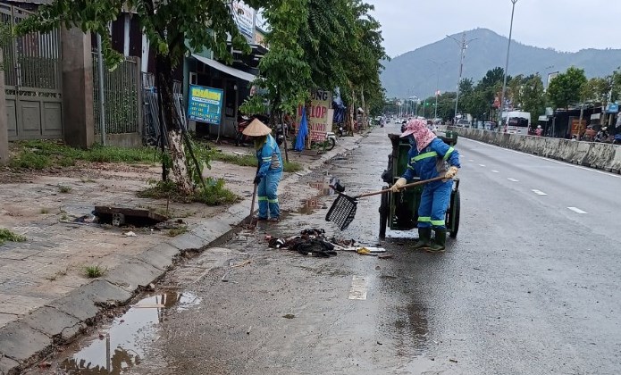 Công nhân Công ty TNHH MTV Môi trường đô thị Hà Nội - Chi nhánh Miền Trung thu gom rác, vệ sinh đường Hoàng Văn Thái sau ngập lụt sâu.