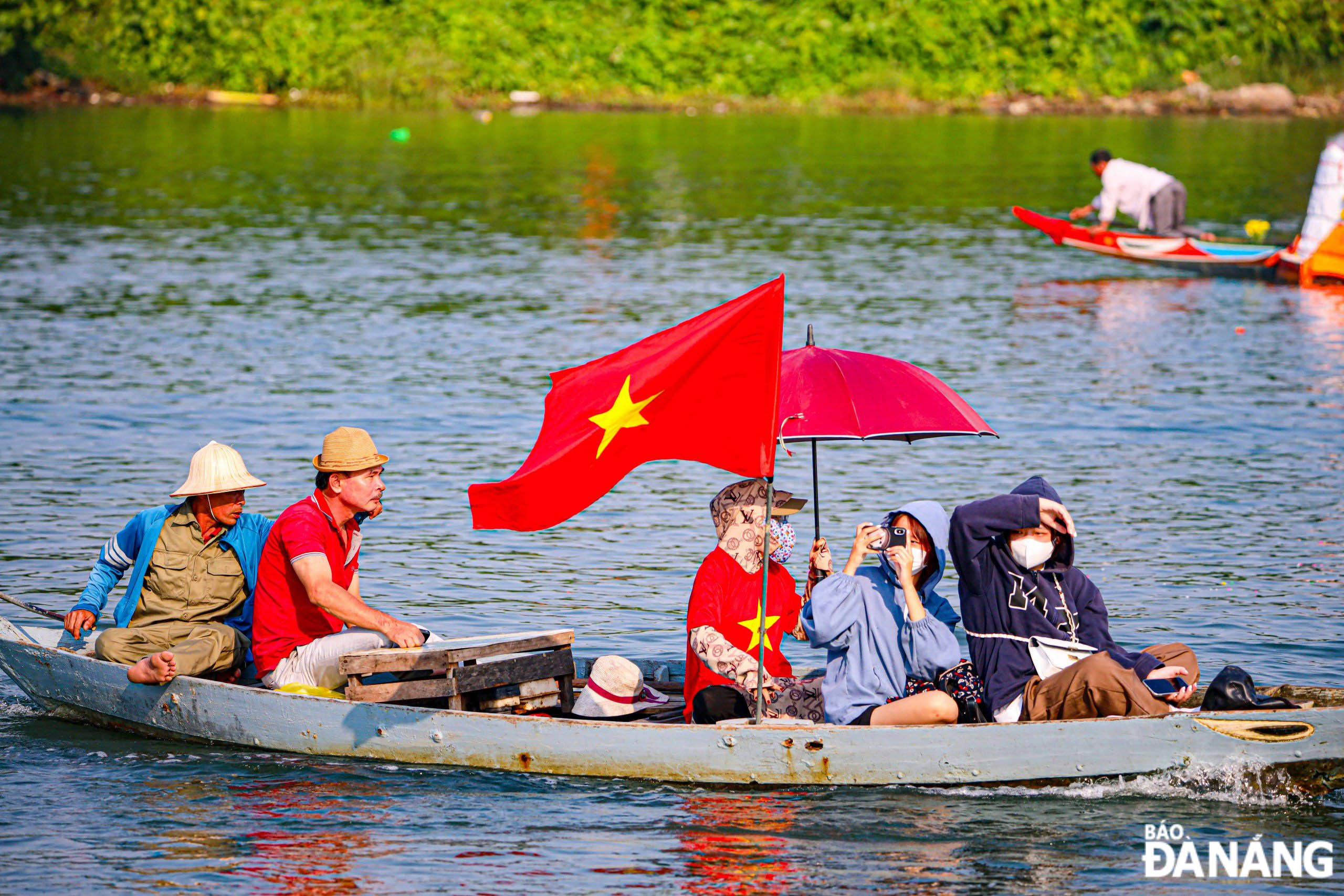 Một gia đình du khách thuê hẳn thuyền máy cắm cờ Tổ quốc để đi cổ vũ cho các đội đua 