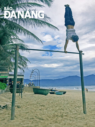 Một bạn trẻ thực hiện động tác khó trong bộ môn Street workout tại bãi biển Phạm Văn Đồng.  Ảnh: H.L