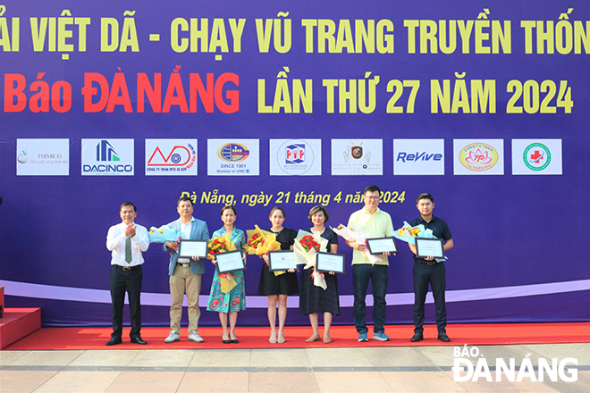 Tổng Biên tập Báo Đà Nẵng, Trưởng Ban tổ chức giải Nguyễn Đức Nam (bên trái) tặng hoa cảm ơn nhà tài trợ.