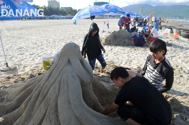 Các thí sinh chăm chú hoàn thành tác phẩm của mình trong phần thi đắp tượng cát.  Trong ảnh: Tác phẩm “Mẹ biển” của nhóm sinh viên Trường Đại học Duy Tân đang được hoàn thiện.           ảnh: Nhật Hạ