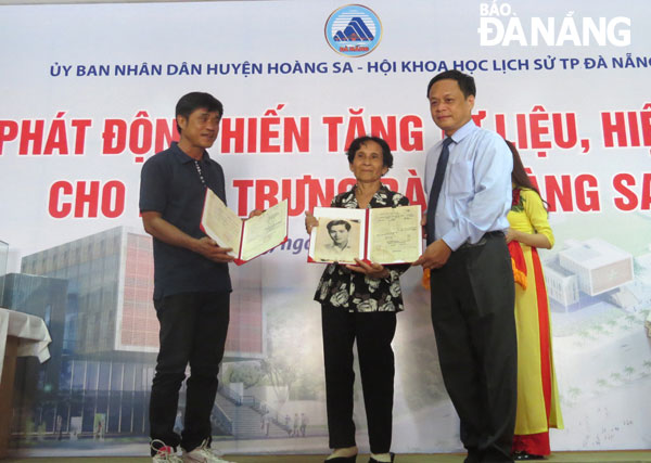 Vợ và con trai Trung sĩ trọng pháo Nguyễn Thành Trọng trao tặng hiện vật cho UBND huyện Hoàng Sa. Ảnh: NGỌC HÀ