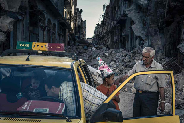 Một gia đình ở phố Homs thu nhặt đồ dùng đưa vào taxi, 6-2014.