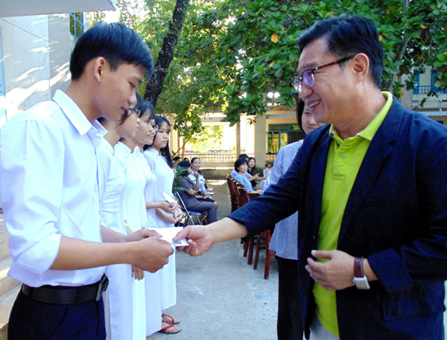 Ông Lý Xương Căn (phải) trao học bổng cho các em học sinh nghèo vượt khó, học giỏi tại Trường THPT Ông Ích Khiêm, huyện Hòa Vang.  			       Ảnh: THANH TUYỀN