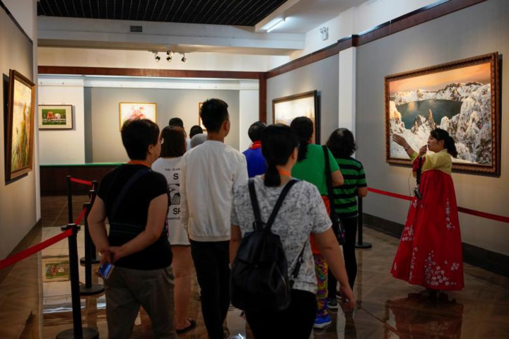 Một nhóm du khách Trung Quốc lắng nghe hướng dẫn viên thuyết trình về một số bức tranh trong triển lãm. 