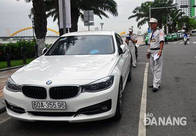 Các cán bộ Đội Kiểm tra quy tắc đô thị quận Hải Châu kiểm tra việc chấp hành thu phí đậu, đỗ ô-tô trên đường Bạch Đằng.