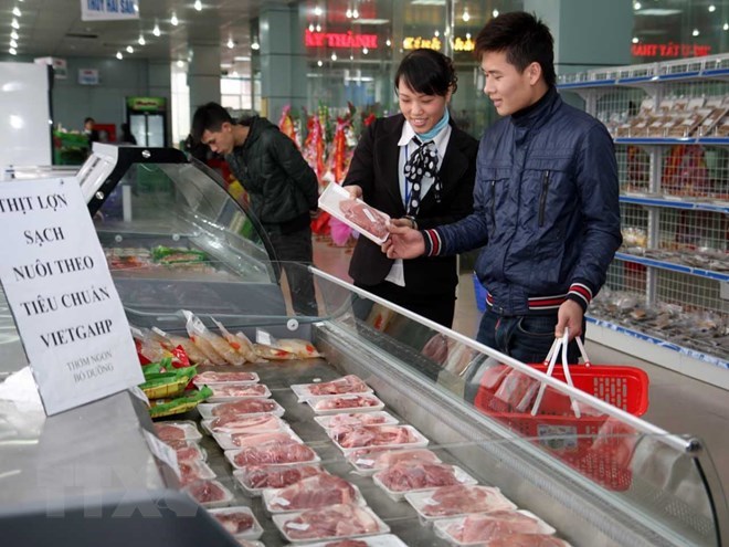 A consumer buys pork at a supermarket (Photo: VNA)