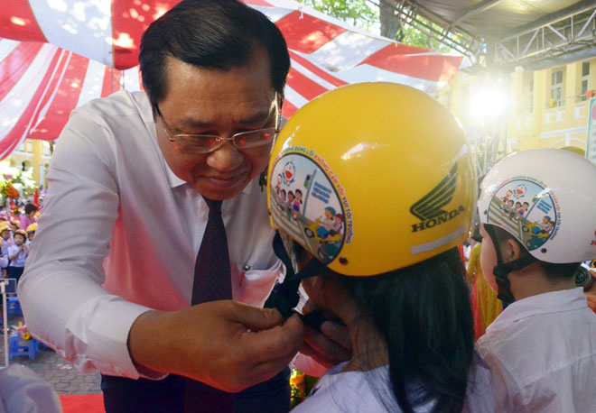 Chairman Tho wearing helmets for Phu Dong primary school pupils 