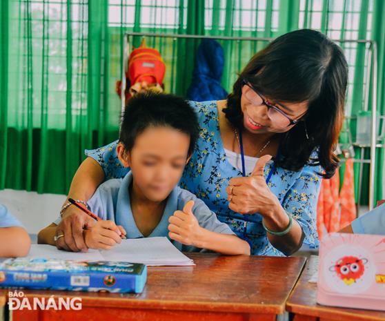 Mrs Do Thi Huu Hanh, Head of the class D1A, has devoted 28 years of her life to teaching and 24 years to working at this school. In picture: She sharing the joy with her student after he wrote letters correctly as per required. 
